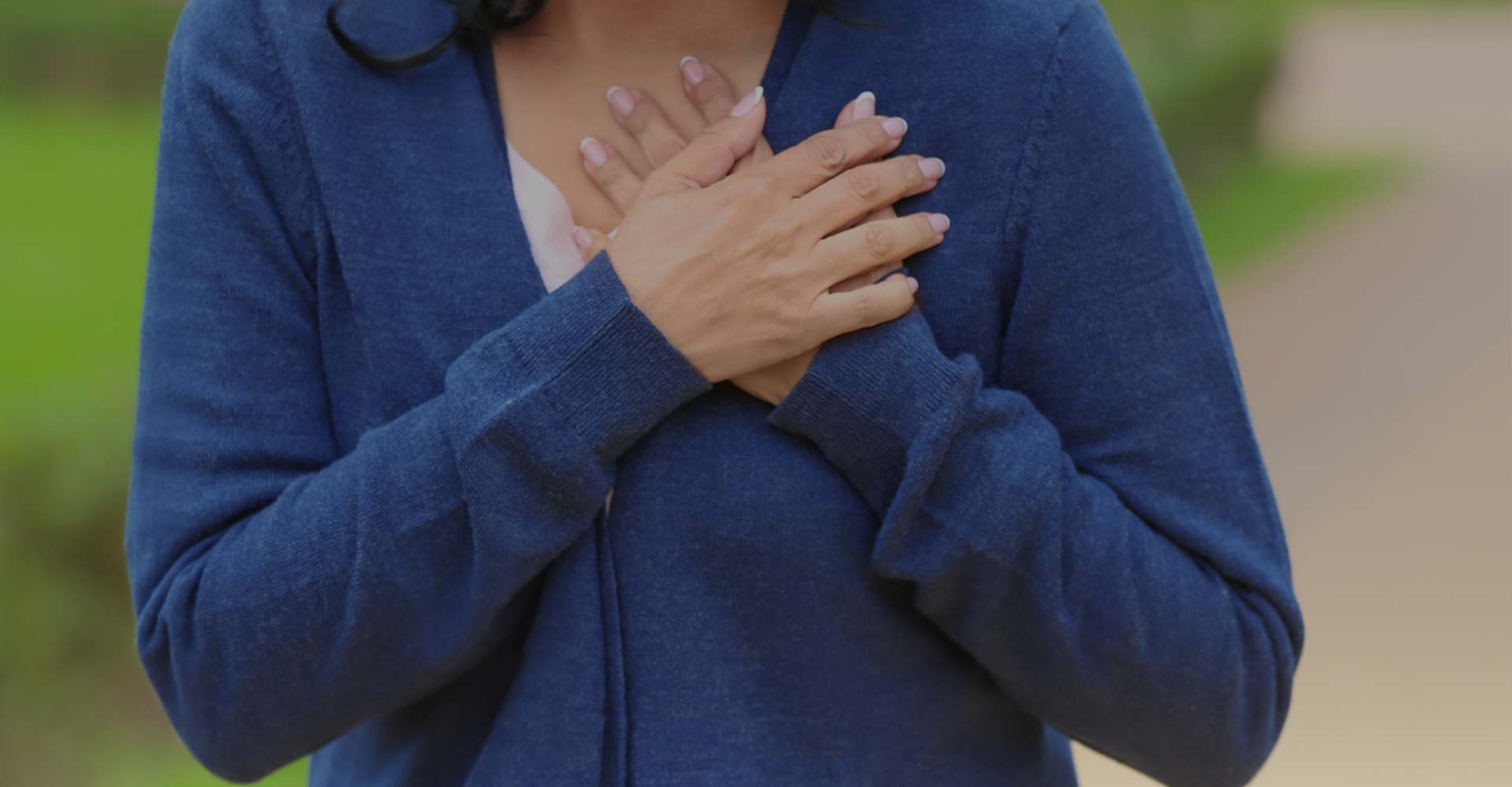 Hands on top of chest where heart is located.