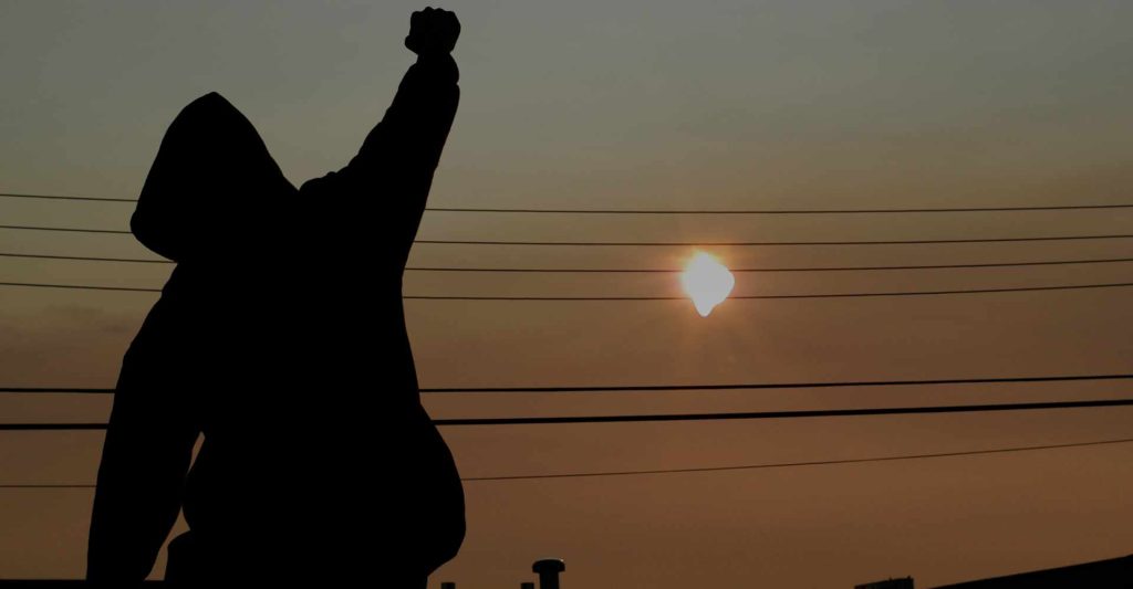 Back of person striking a heroic pose with sunset in background