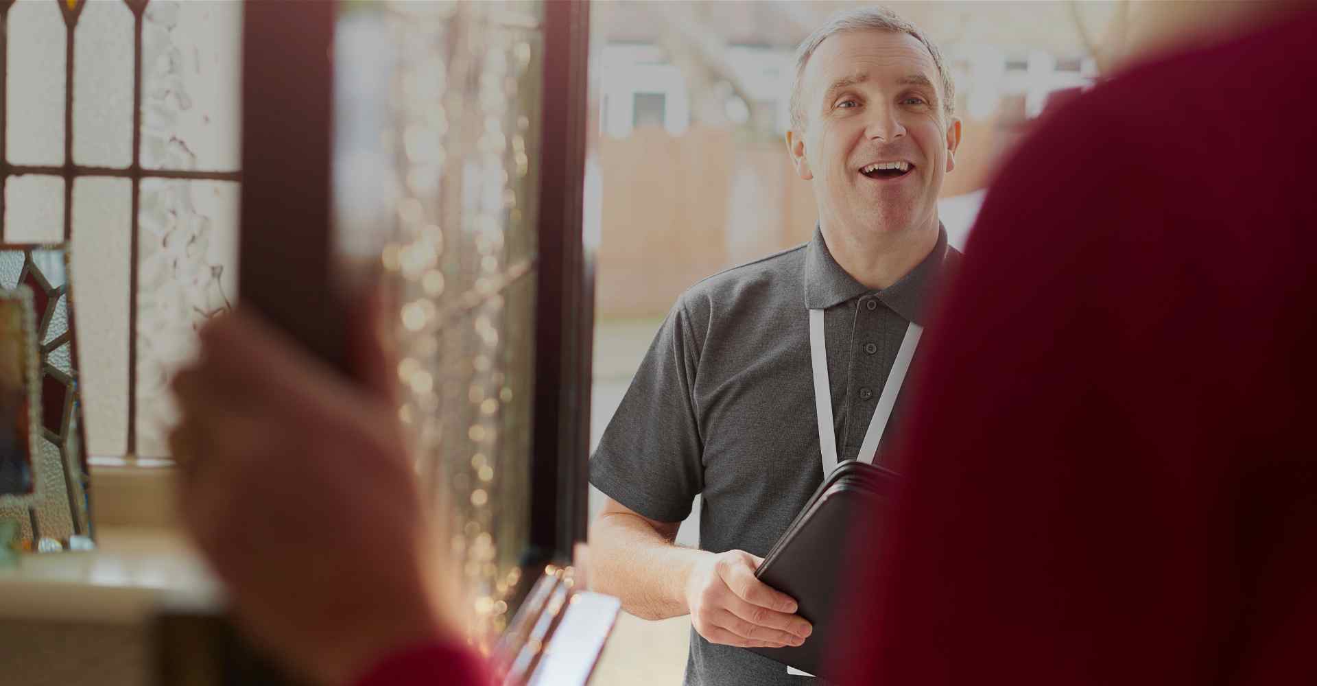 White man who is a home visiting professional in the open doorway of a families house introducing himself.