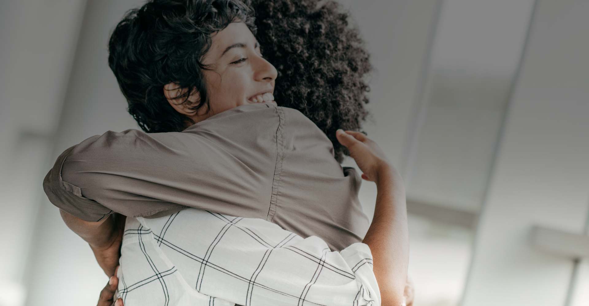 Two people in a group therapy session giving each other a hug.