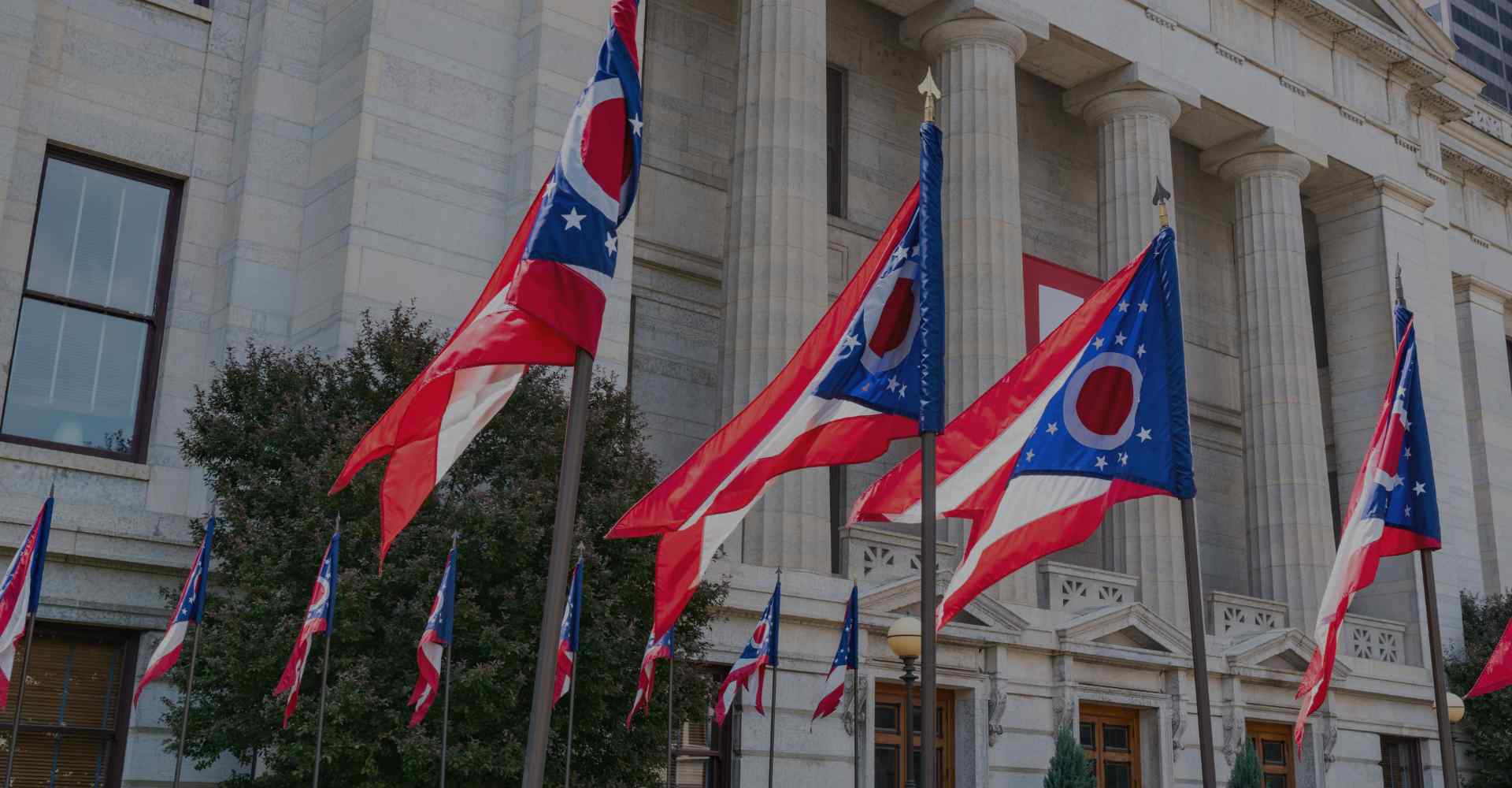 A line of Ohio state flags in front of a government building.