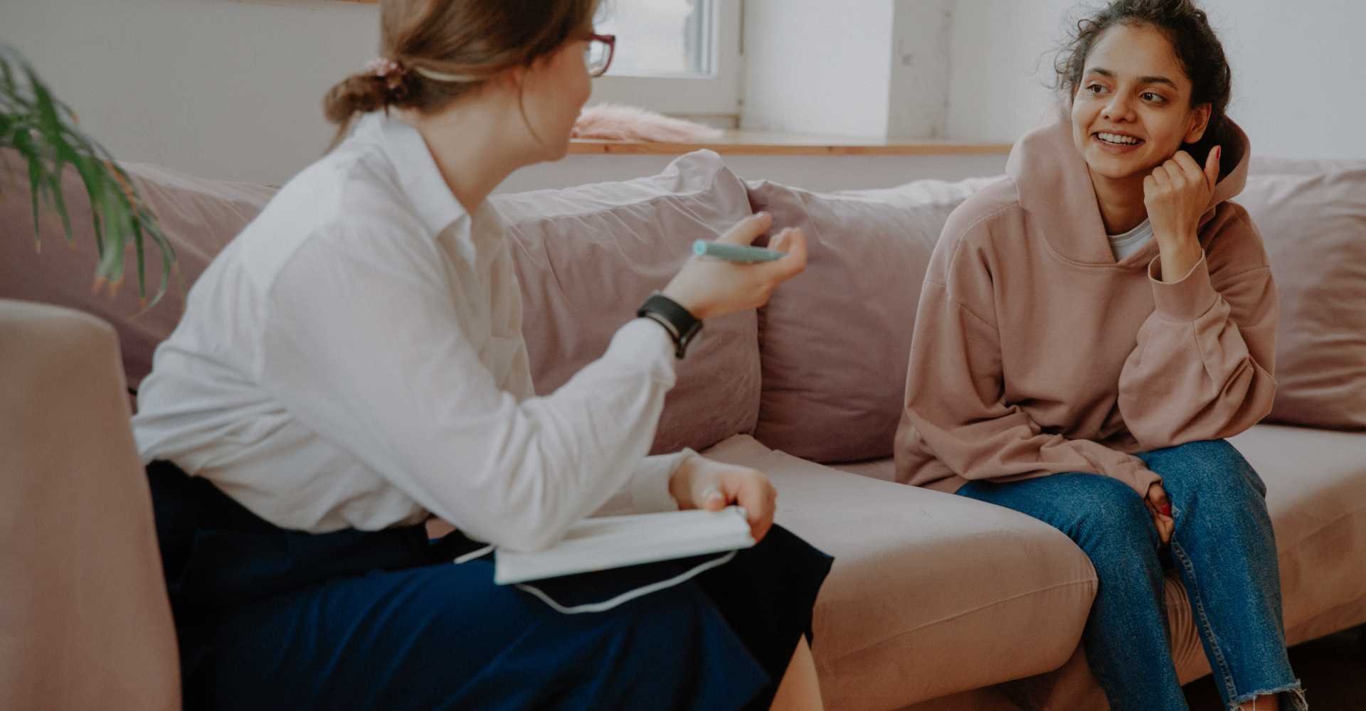 Young white woman client discussing her therapy journey with white counselor.