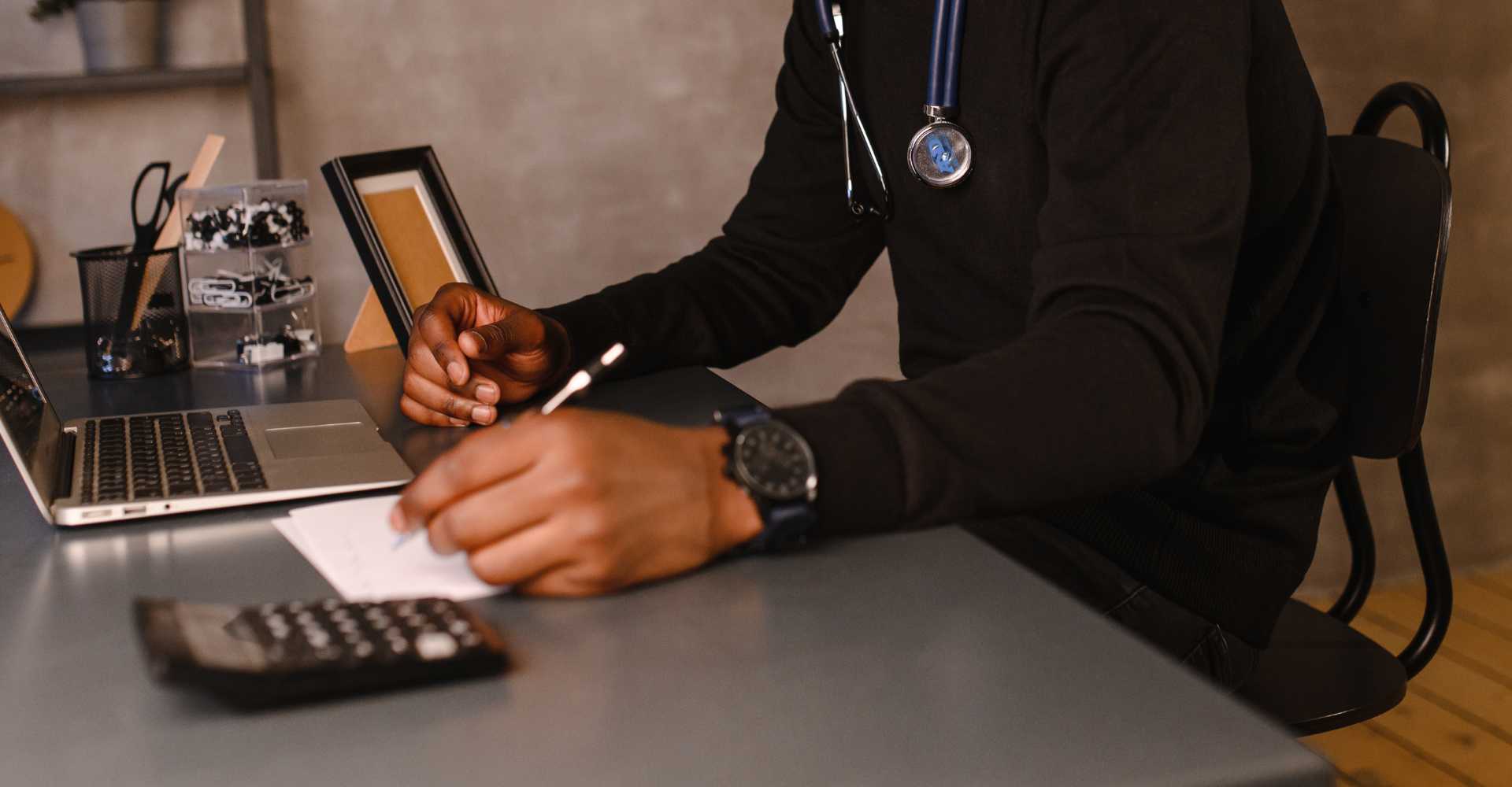 Telehealth provider completing paperwork at desk.