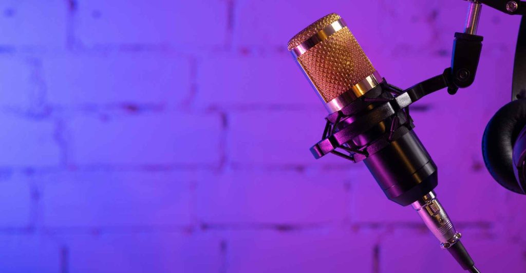 Podcast microphone in front of brick wall highlighted with purple light.