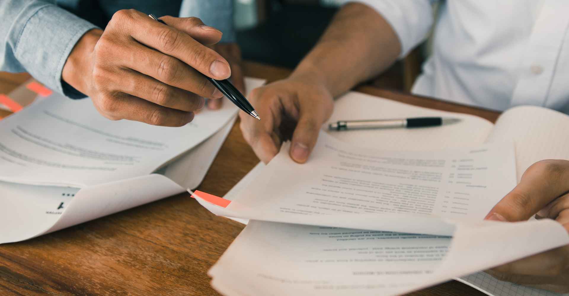 Hands of two people discussing research publication edits.