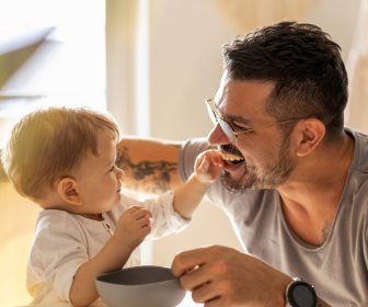 Happy white baby feeding smiling dad