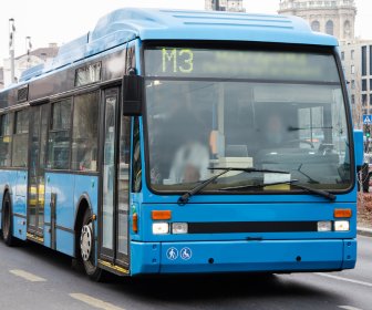 A city bus driving on the street representing access to transportation as one of the social drivers. 