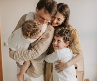 White family of four embracing each other joyfully.