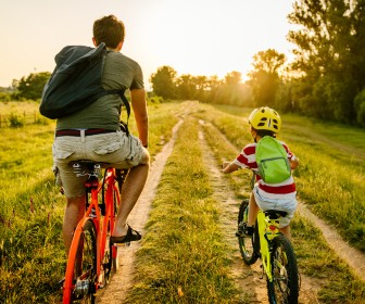 Dad and his son on a bike ride on a dirt road celebrating fatherhood. 