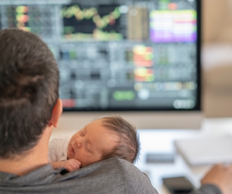 Dad holding newborn while working as he was unable to take paid paternal leave.