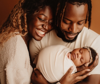 Proud and joyful Black mom and dad holding baby in a professional newborn photoshoot 