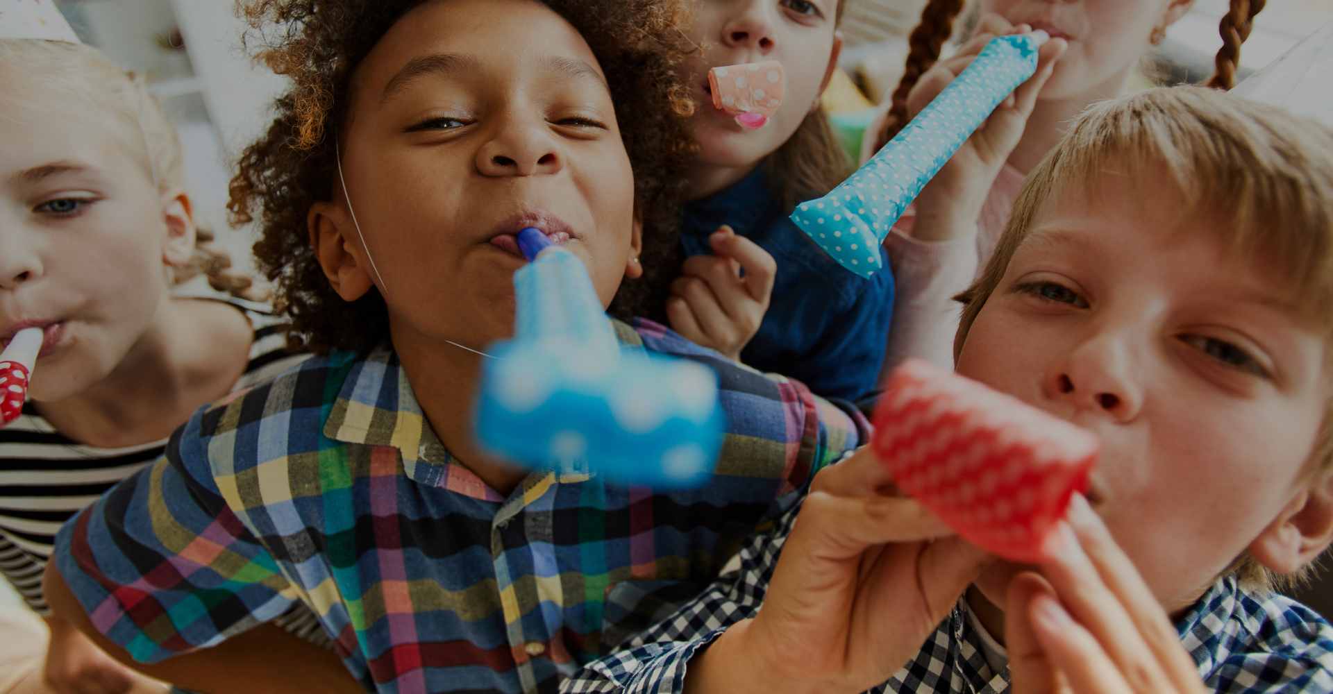 Diverse kids at a party using party blowouts to celebrate.