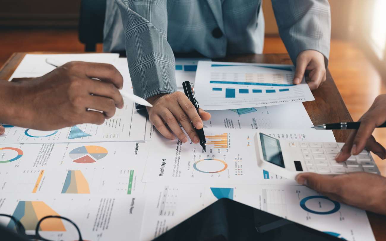 Three diverse researchers discuss data charts using their hands.