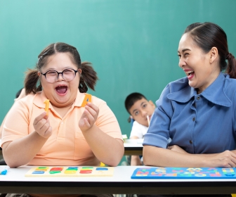 Teacher and girl with down syndrome interacting joyfully together.