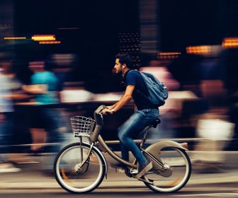 A man riding a bike in a busy city, representing a client with unique therapeutic needs due to lack of access to a car or public transportation.