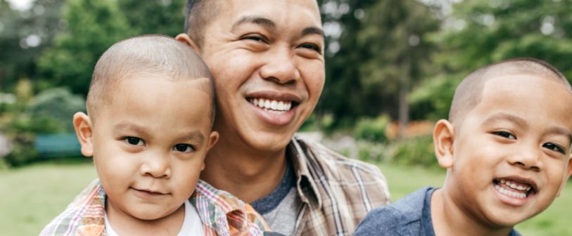 Asian dad smiling joyfully with his two sons.