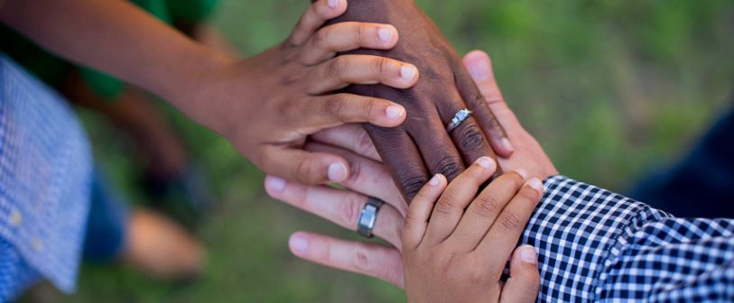 Diverse family hands in a stack on top of the dad's hand.