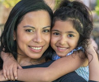 Hispanic mom and daughter hugging