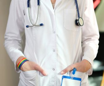 LGBTQ+ doctor who underwent LGBTQ+ cultural competency training wearing a LGBTQ+ pride flag bracelet. 