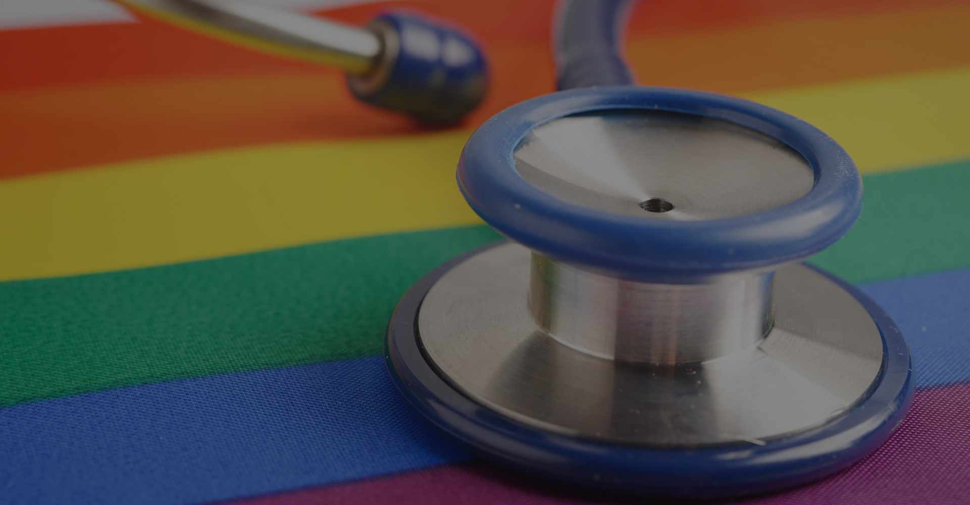 A stethoscope on top of an LGBTQ+ pride flag.