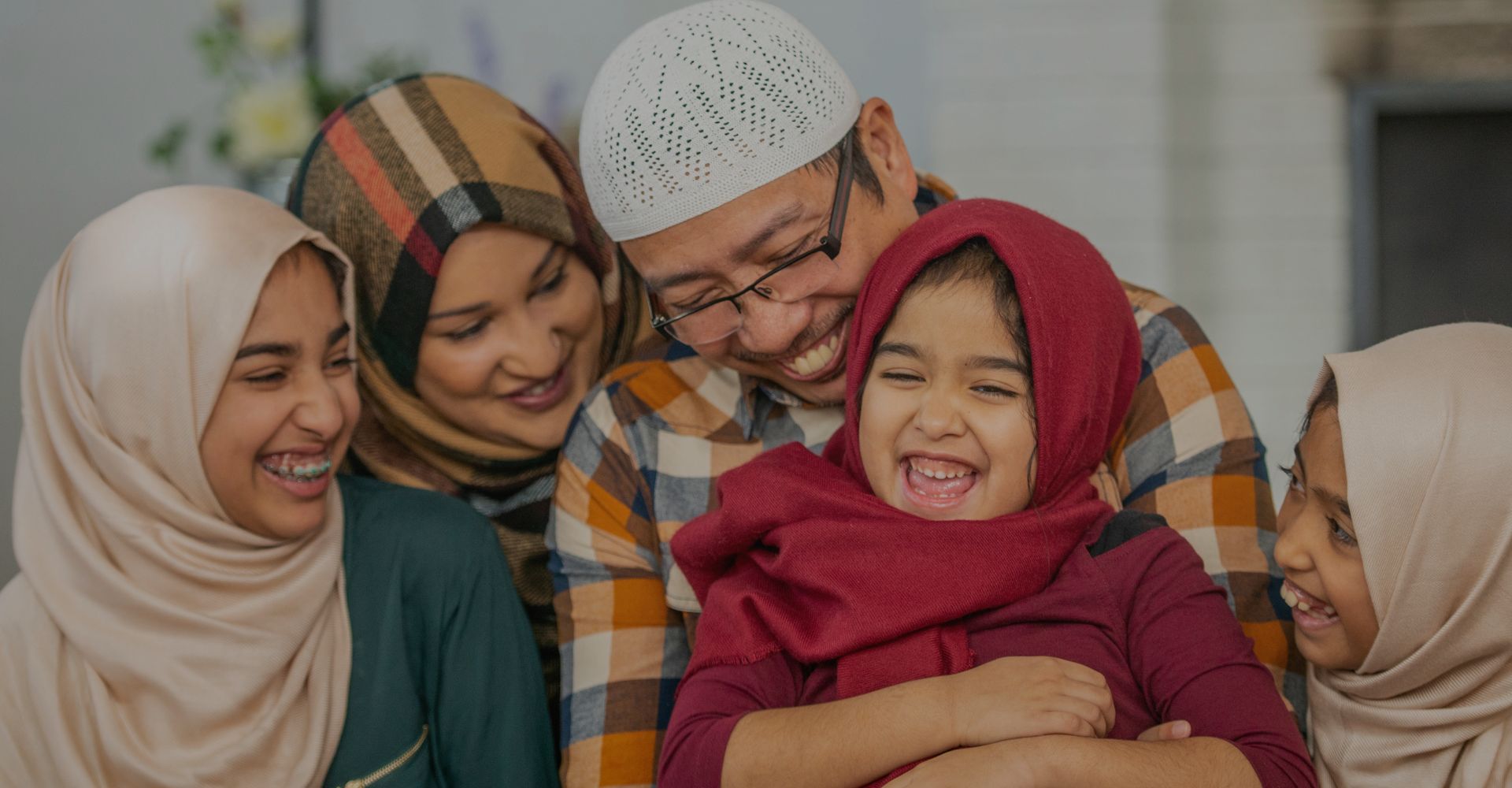 Muslim family of five sitting and laughing together.