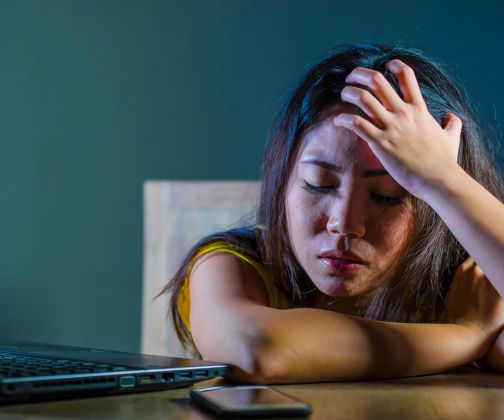 Asian woman overwhelmed by online mental health stigma.