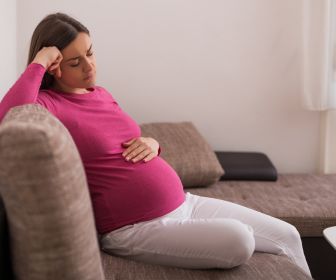 Pregnant mom with a sad expression on face as she explores her experiences of parent ACEs in a therapy session.