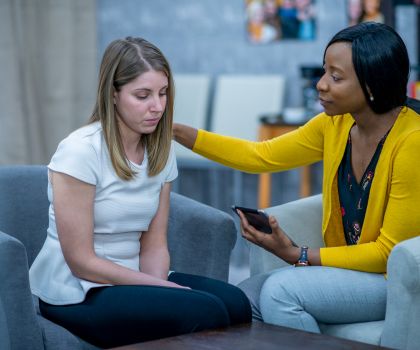 Black therapist compassionately comforting white client who is in distress.