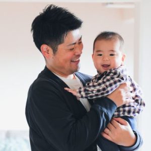 Asian dad and baby smiling together.