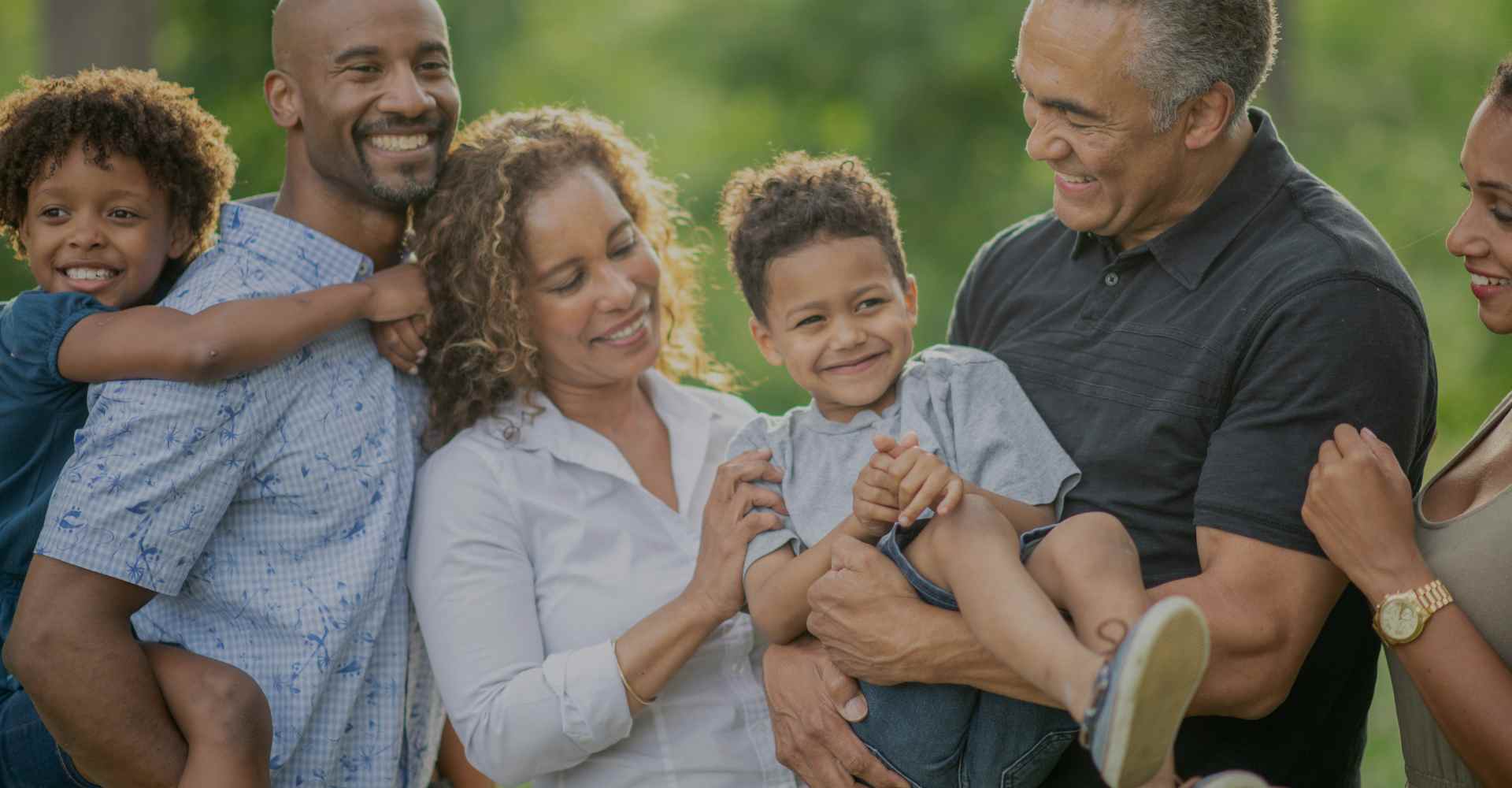 Hispanic and Black parents and grandparents smiling joyfully while holding two young boys