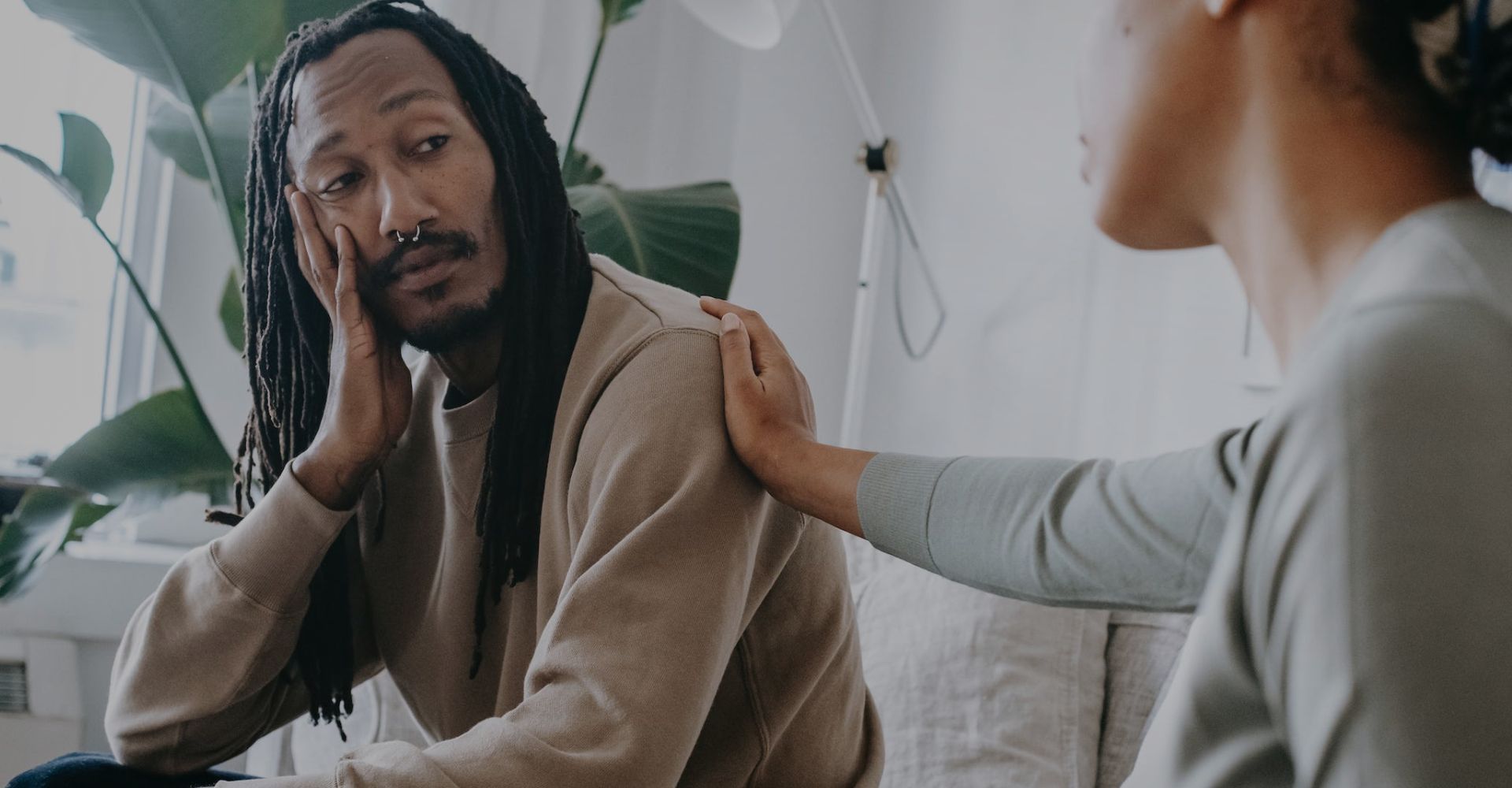 Black man being comforted by his therapist in session.