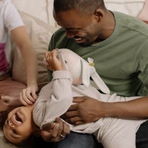 Black dad holding daughter while they both laugh